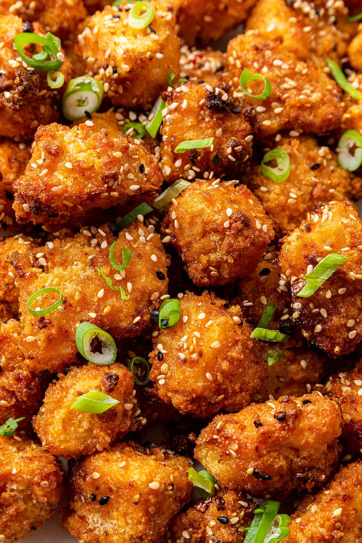 Close up of a bang bang cauliflower topped with sesame seeds and scallions