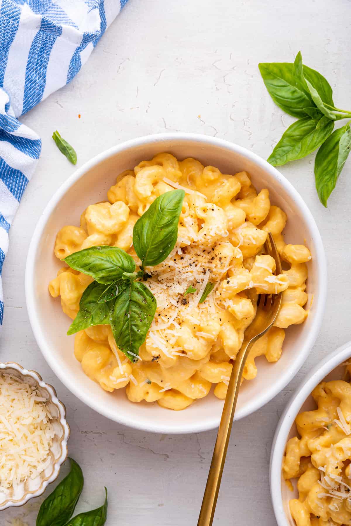 Bowl of butternut squash mac and cheese garnished with parmesan and sprig of basil