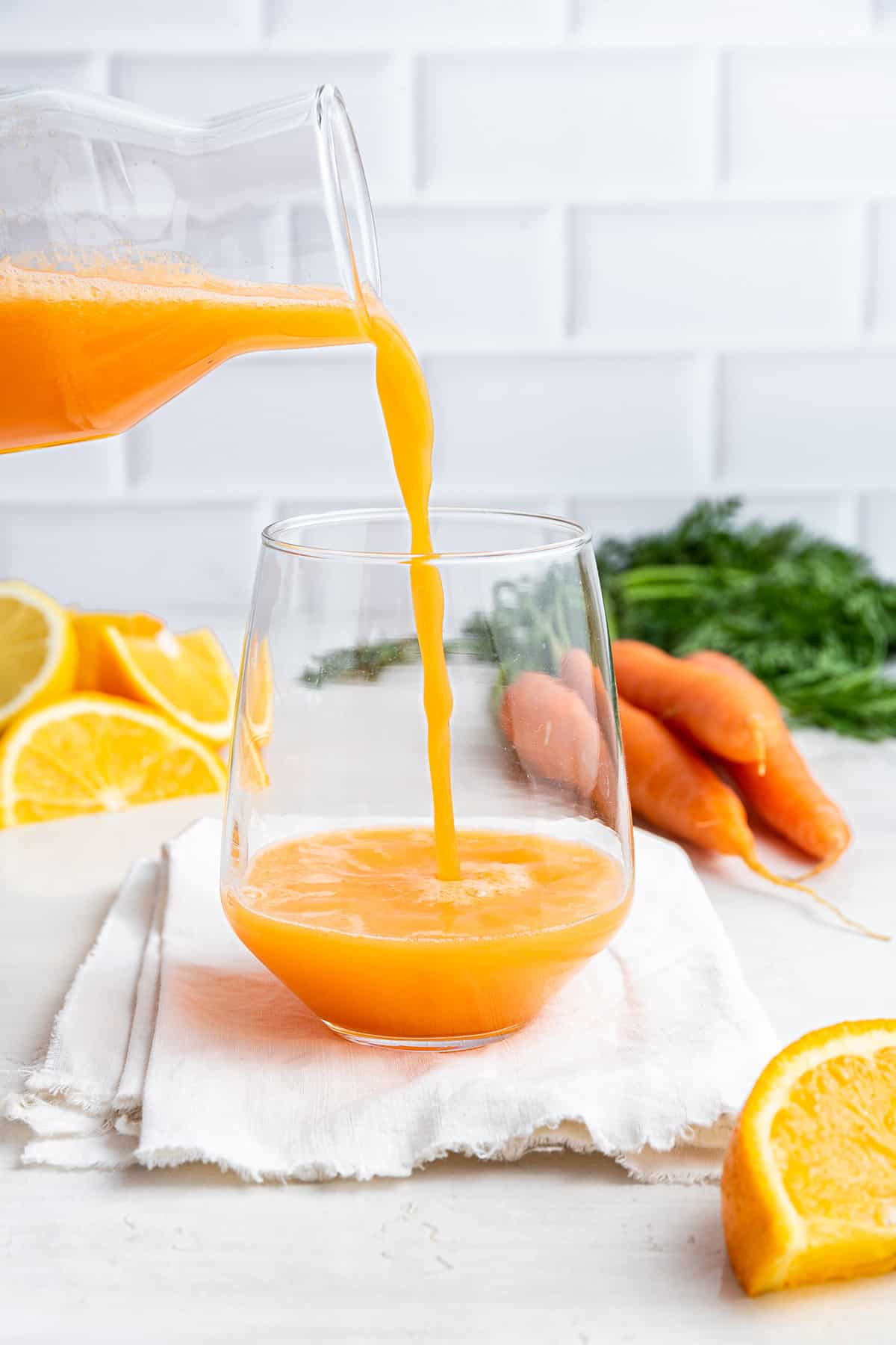Pouring carrot juice from carafe into glass