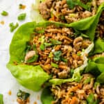 A tray of chicken lettuce wraps surrounded by sliced scallions