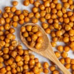 A counter full of crispy chickpeas, with a wooden spoon in the middle with chickpeas