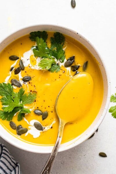 white bowl of curried acorn squash soup with pumpkin seeds