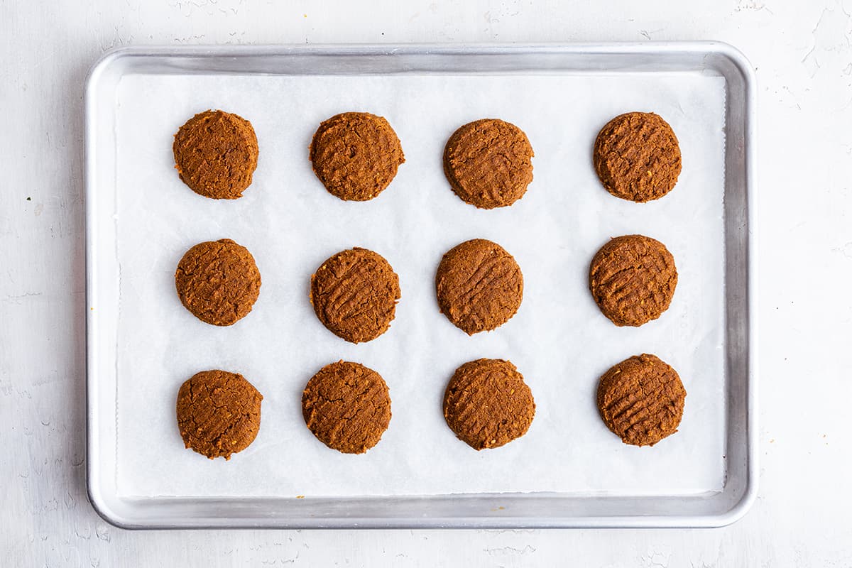Overhead view of baked pumpkin cookies on parchment-lined sheet pan