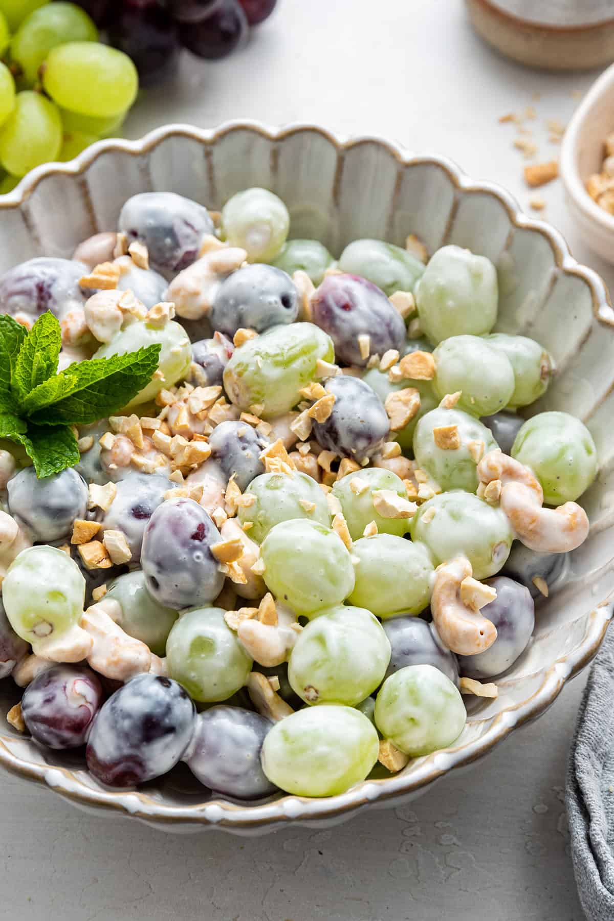 Close up of a fruit salad with red and green grapes, cashews, and yogurt