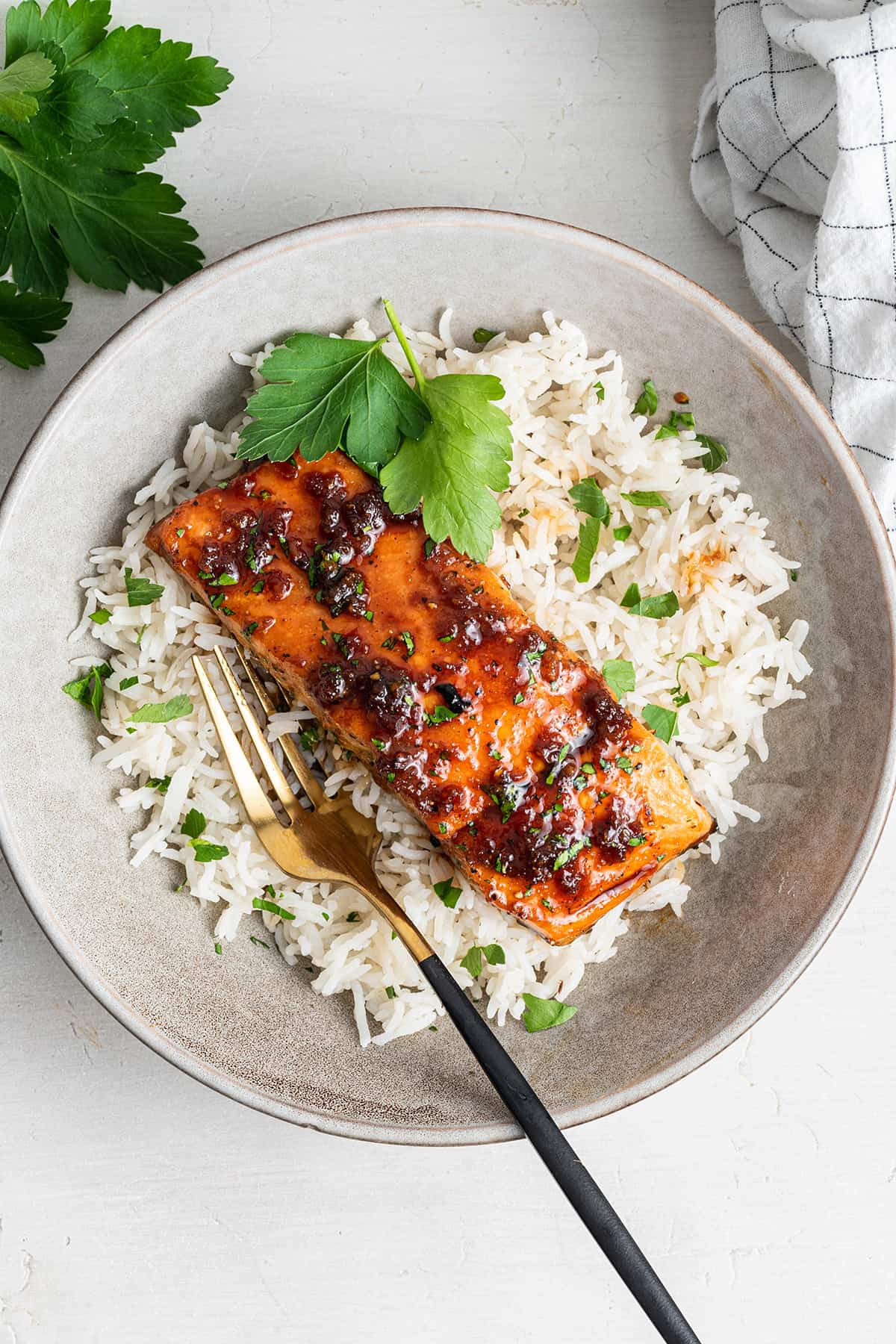 Overhead view of a fillet of honey glazed salmon on top of a bed of cilantro rice, with a fork