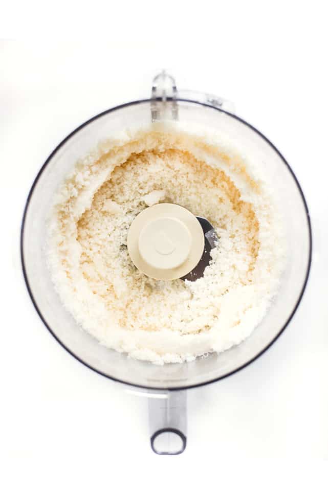 Overhead view of coconut in a food processor, looking fluffy and soft