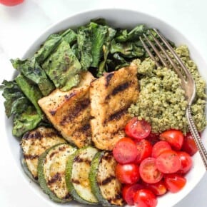 bowl of pesto quinoa with grilled tofu, tomatoes, grilled zucchini and kale