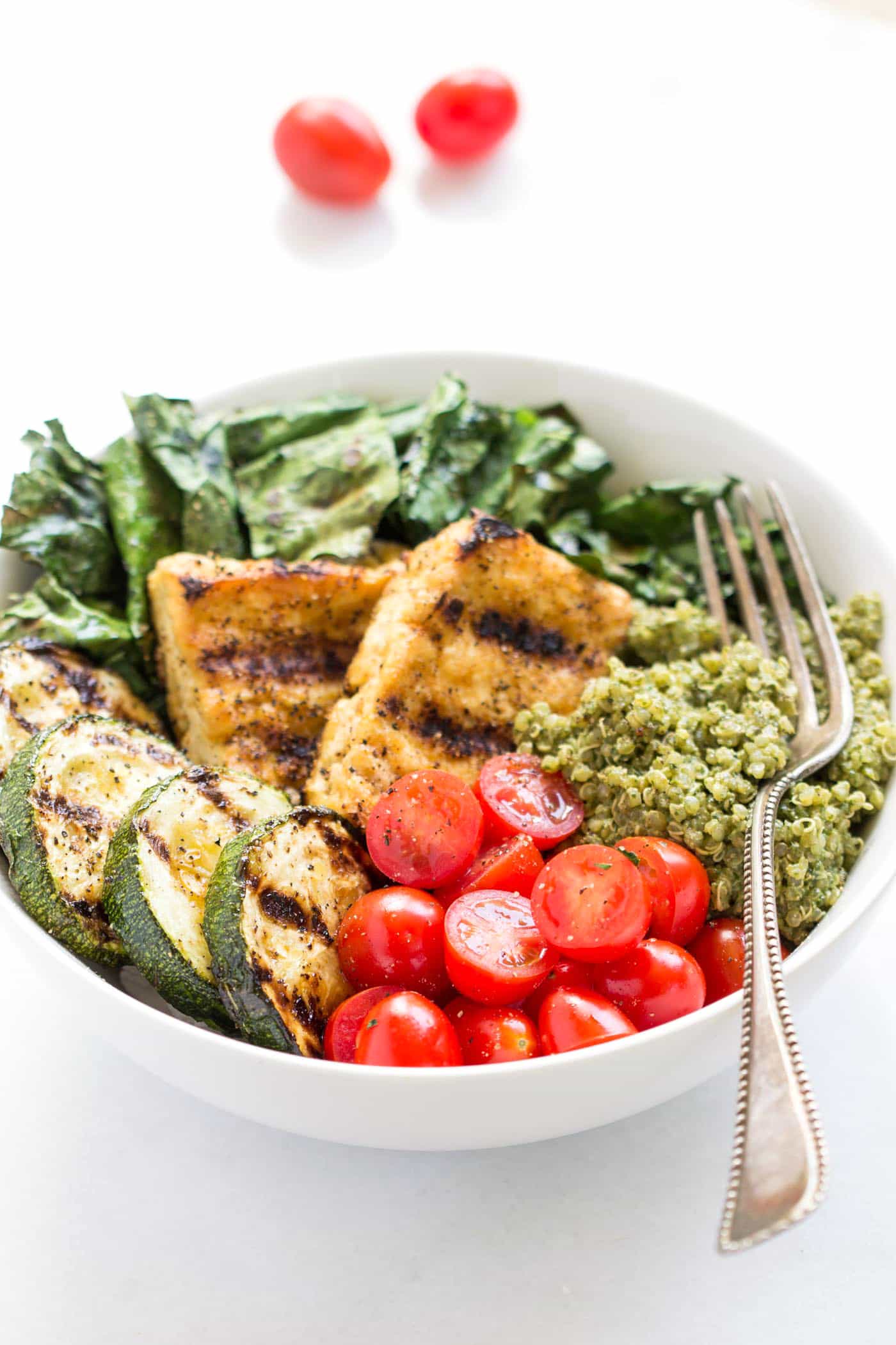 These simple pesto quinoa bowls are amazing! Topped with grilled veggies, tofu and chopped cherry tomatoes!