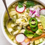 Overhead view of chicken pozole verde in bowl with spoon