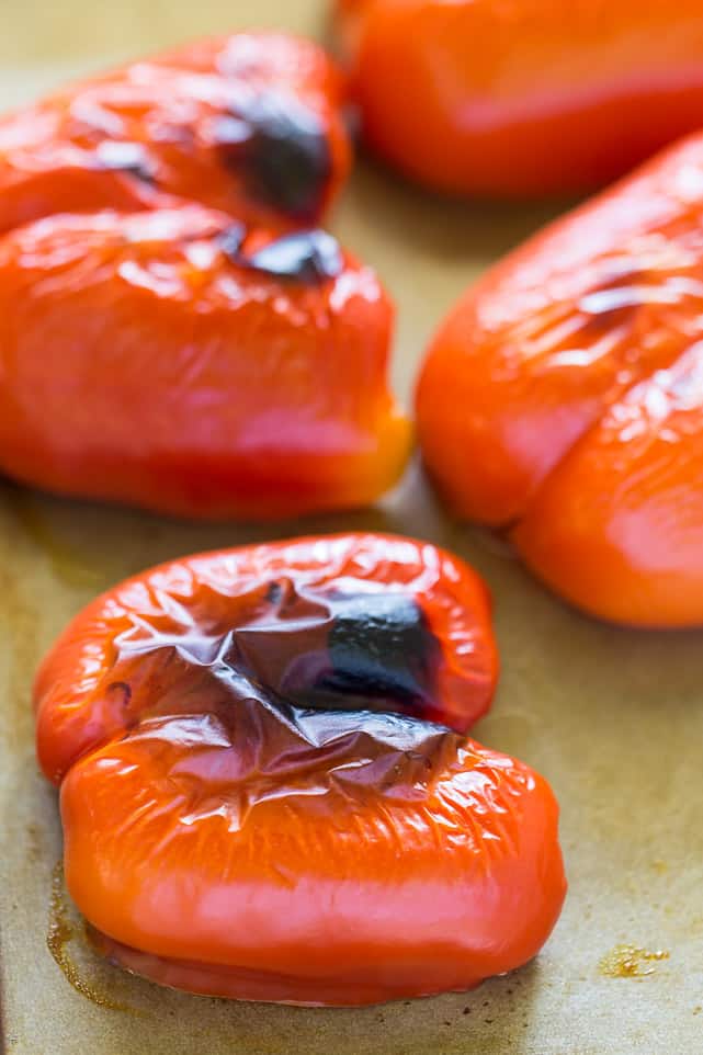 Half of a red bell pepper that's black and charred on top, with three more surrounding it