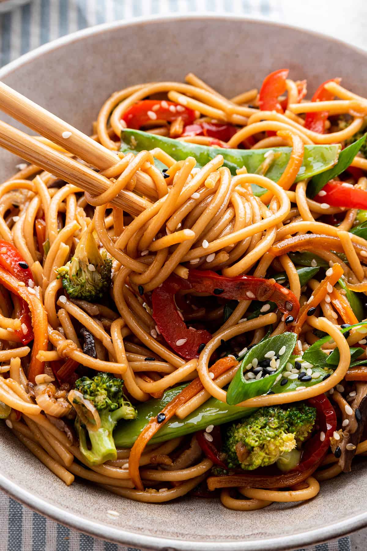 Chopsticks wrapped with vegetable lo mein noodles in bowl