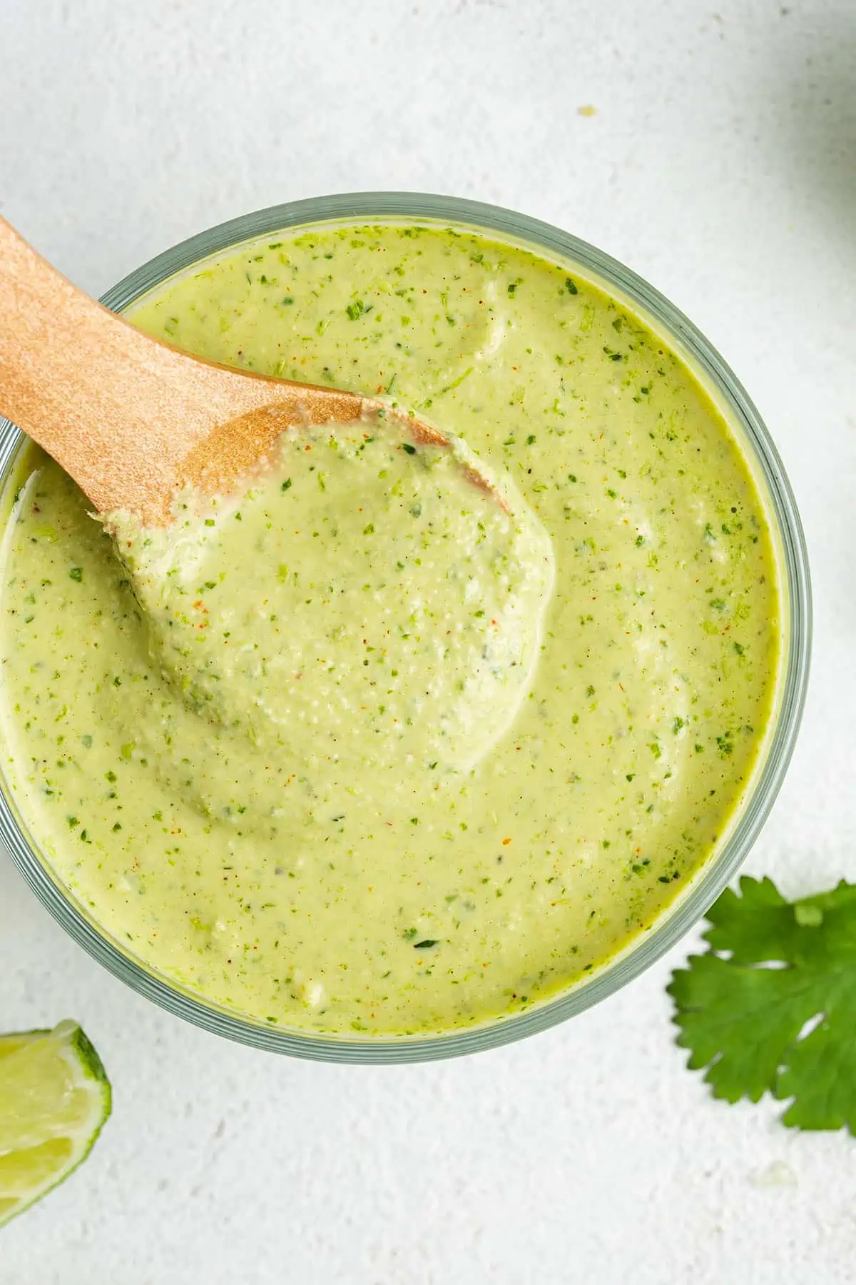Overhead view of a jar of cilantro lime sauce with a wooden spoon in it