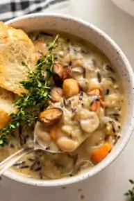 spoon of creamy wild rice soup with thyme and bread