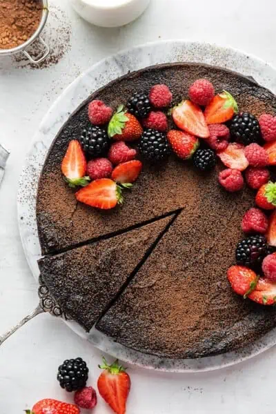 A slice being removed from a flourless dark chocolate cake