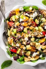 close up on a large bowl of grilled vegetable salad with tahini dressing and feta cheese