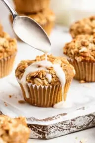 pouring white glaze over an apple cinnamon muffin