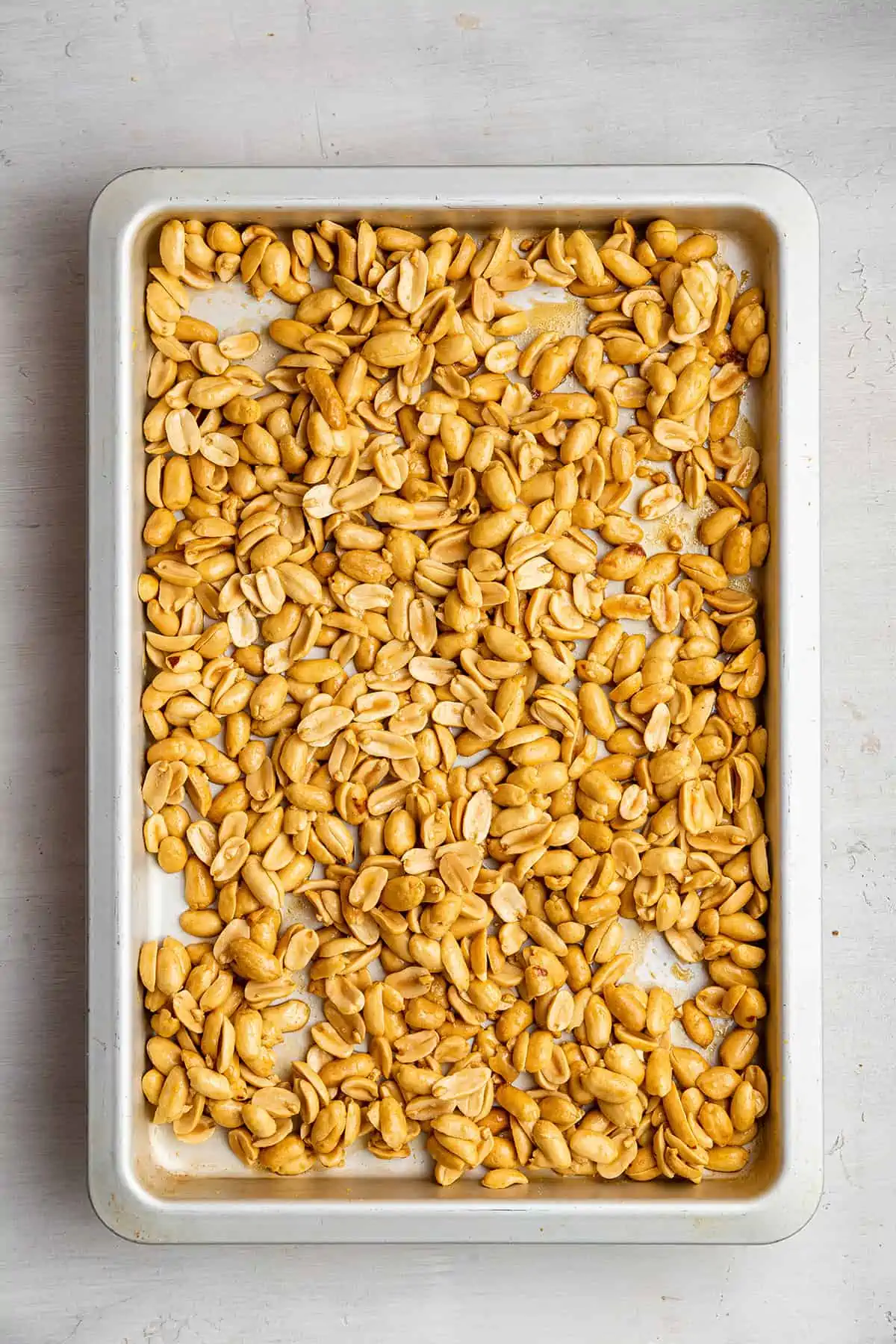 A baking tray with peanuts, honey, and salt on it