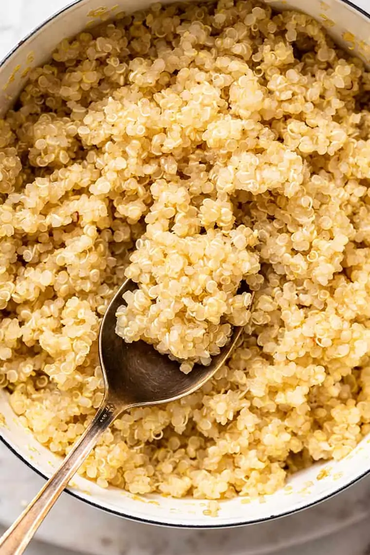 Close up of a spoon taking a spoonful of quinoa out of a bowl