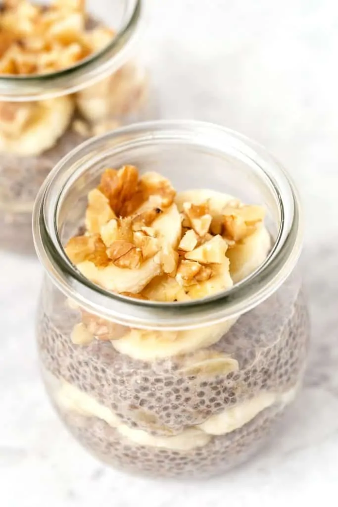 Chia pudding in a glass jar, topped with sliced bananas and walnuts