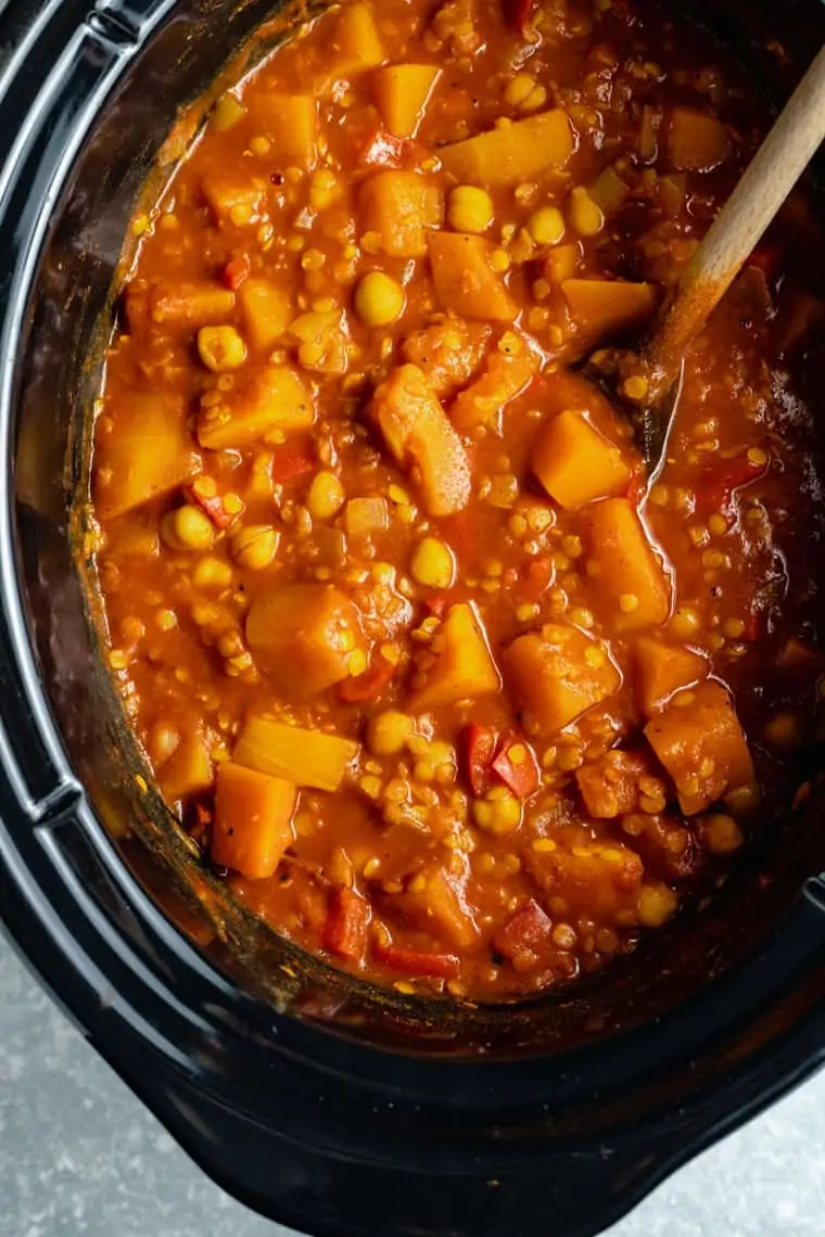 overhead of a black slow cooker with chickpea, lentil and butternut squash stew