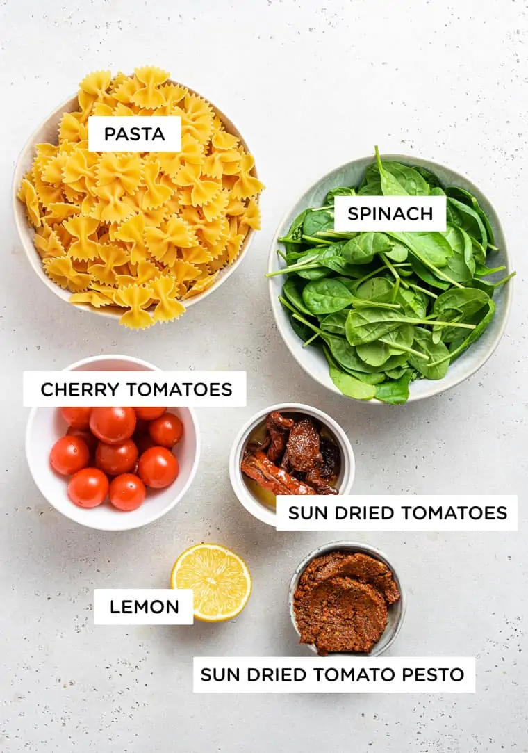ingredients for pasta with spinach, cherry tomatoes, sundried tomatoes and lemon